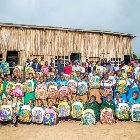 Group of Ugandan students proudly displaying Ecojua Smart Bags made from recycled plastic, distributed by Smart Girls Uganda to promote education, menstrual health, and sustainability.