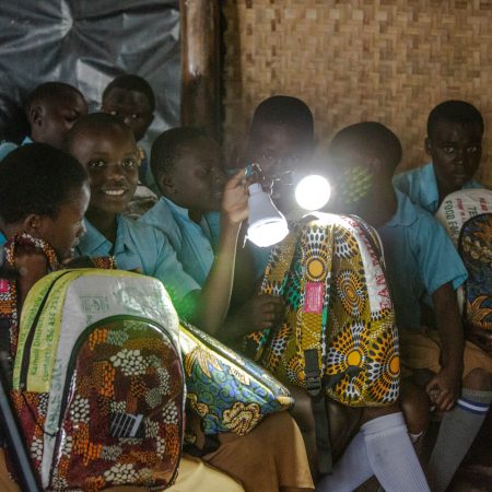 Students using Ecojua Smart Bags with built-in solar lights, part of Smart Girls Uganda’s innovation improving study conditions and reducing school absenteeism in off-grid communities.