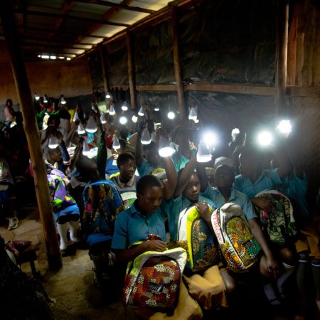 Students using solar-powered Ecojua Smart Bags for lighting in a classroom, part of Smart Girls Uganda’s initiative to support off-grid education and empower girls through sustainable innovation.