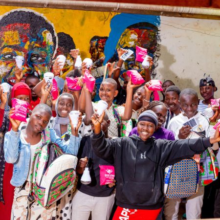 Group of girls in Uganda holding Ecojua Smart Bags, reusable menstrual kits, and solar lamps distributed by Smart Girls Uganda to promote menstrual health, education, and sustainability.